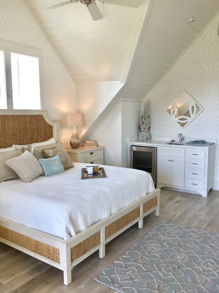 This is an example of a coastal bedroom in Austin with white walls and light hardwood flooring.