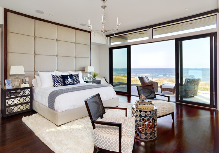 На фото: хозяйская спальня в морском стиле с белыми стенами, деревянным полом и коричневым полом без камина с