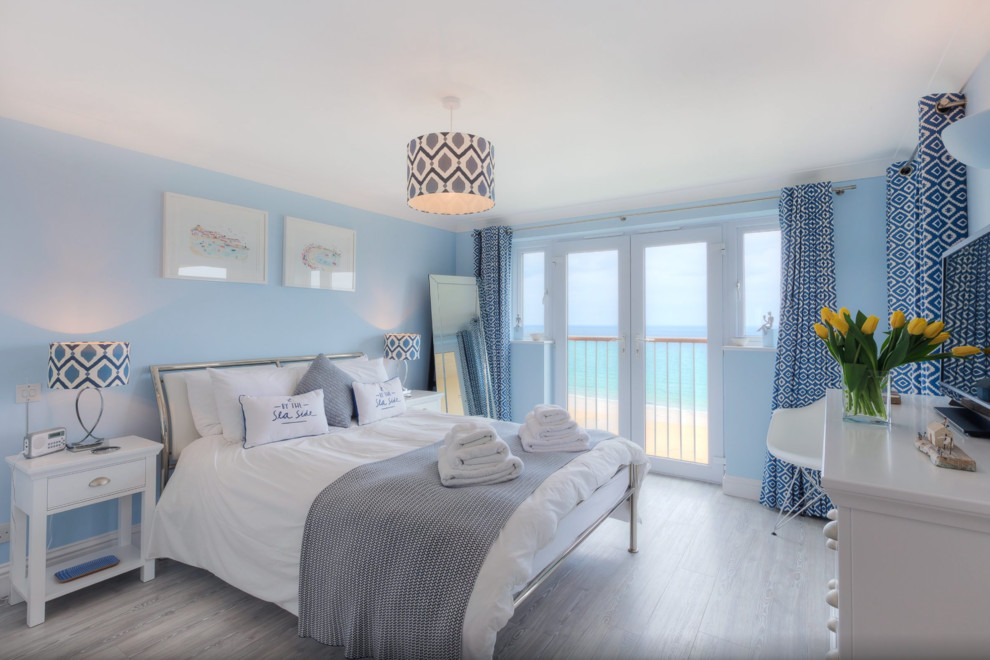 Aménagement d'une chambre bord de mer de taille moyenne avec un mur bleu, parquet clair et aucune cheminée.