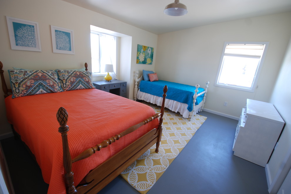 Exemple d'une chambre mansardée ou avec mezzanine bord de mer de taille moyenne avec un mur blanc et sol en béton ciré.