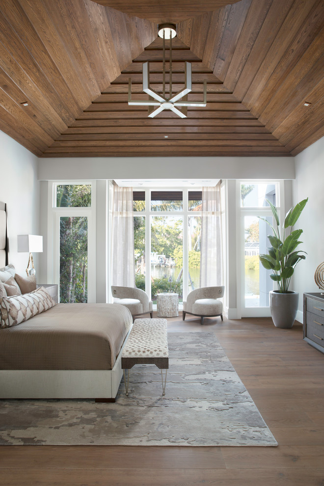 Modelo de dormitorio costero con paredes blancas, suelo de madera en tonos medios y suelo marrón