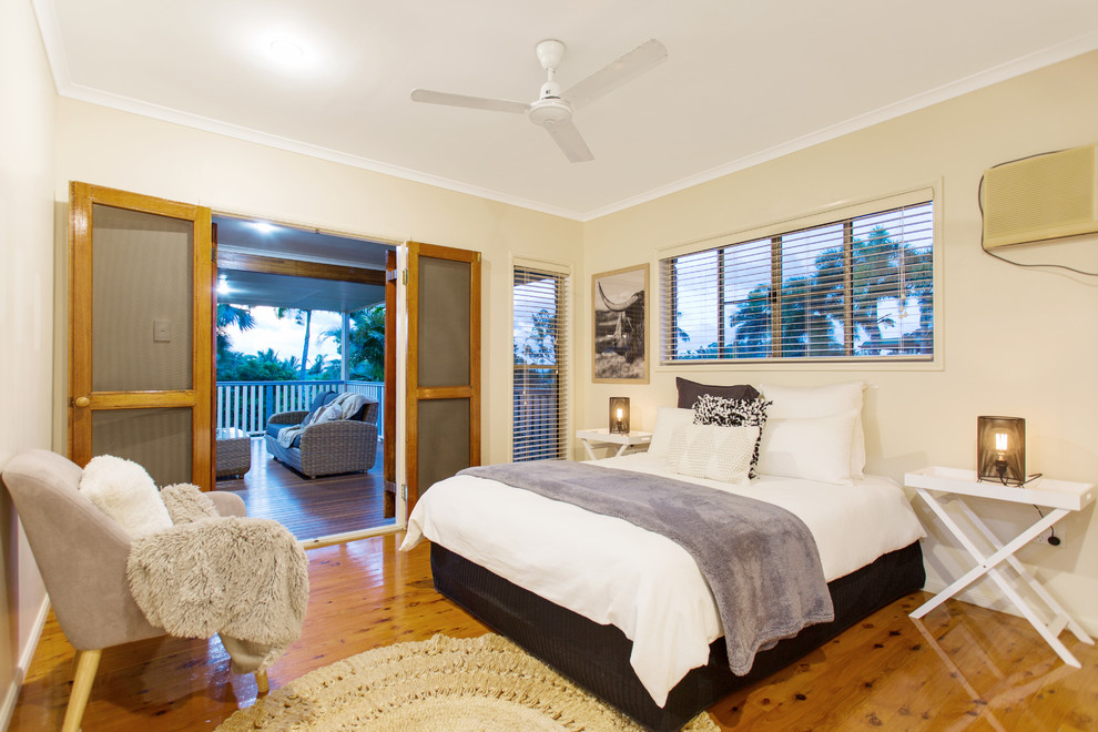 Diseño de dormitorio principal costero con paredes beige, suelo de madera en tonos medios y suelo marrón