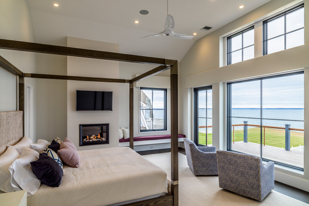 На фото: хозяйская спальня в морском стиле с серыми стенами, темным паркетным полом и горизонтальным камином