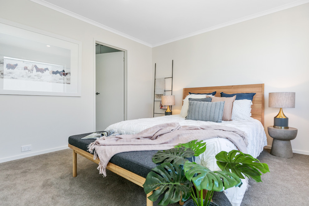 Modelo de dormitorio principal costero con paredes beige, moqueta y suelo gris