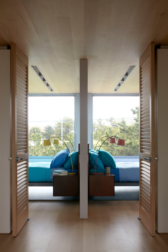 Modelo de habitación de invitados costera con suelo de madera en tonos medios