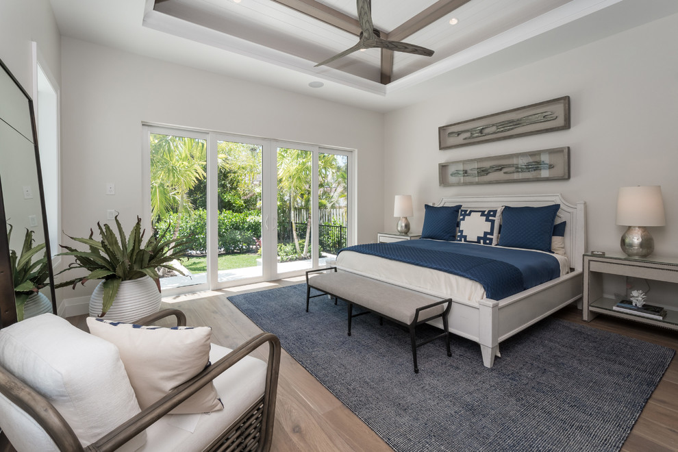 Photo of a nautical master, grey and brown and grey and silver bedroom in Miami with white walls, medium hardwood flooring and brown floors.