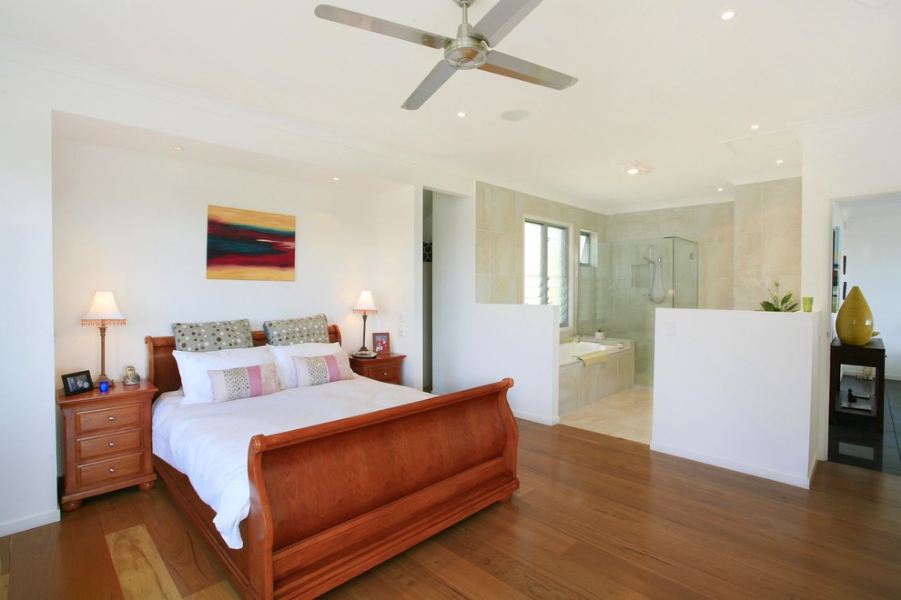 Exemple d'une chambre tendance avec un mur blanc et un sol en bois brun.