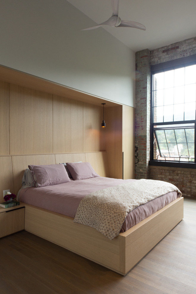 Foto de dormitorio principal urbano de tamaño medio sin chimenea con paredes grises, suelo de madera en tonos medios y suelo marrón