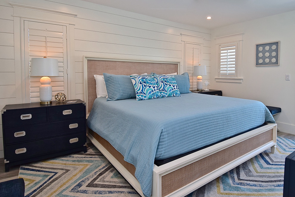 タンパにある広いビーチスタイルのおしゃれな主寝室 (白い壁、磁器タイルの床、ベージュの床) のレイアウト