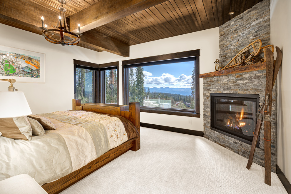 Uriges Hauptschlafzimmer mit weißer Wandfarbe, Teppichboden, Eckkamin und Kaminumrandung aus Stein in Vancouver