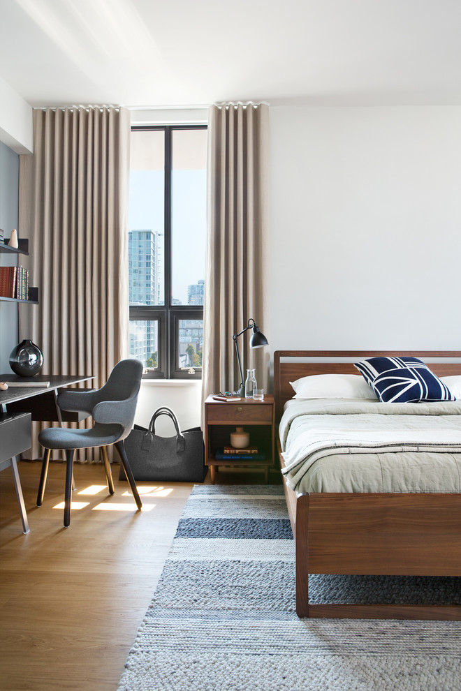 Modelo de dormitorio principal moderno de tamaño medio sin chimenea con paredes blancas y suelo de madera en tonos medios