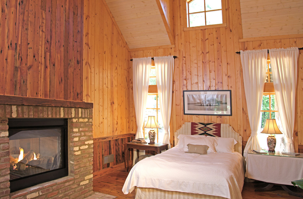 Пример оригинального дизайна: спальня среднего размера в стиле кантри с паркетным полом среднего тона, двусторонним камином и фасадом камина из кирпича