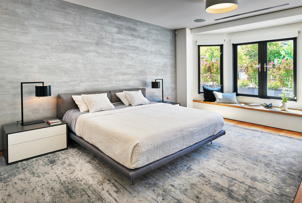 Modelo de dormitorio principal contemporáneo grande con paredes grises, suelo de madera en tonos medios, suelo marrón y papel pintado