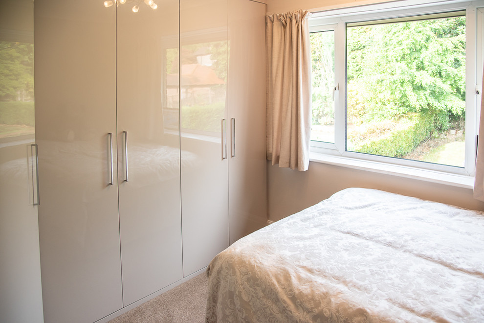Imagen de dormitorio tipo loft actual de tamaño medio sin chimenea con paredes beige, moqueta y suelo beige