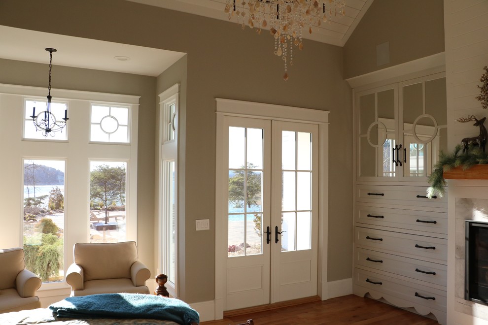 Large cottage master medium tone wood floor bedroom photo in Other with gray walls, a standard fireplace and a wood fireplace surround