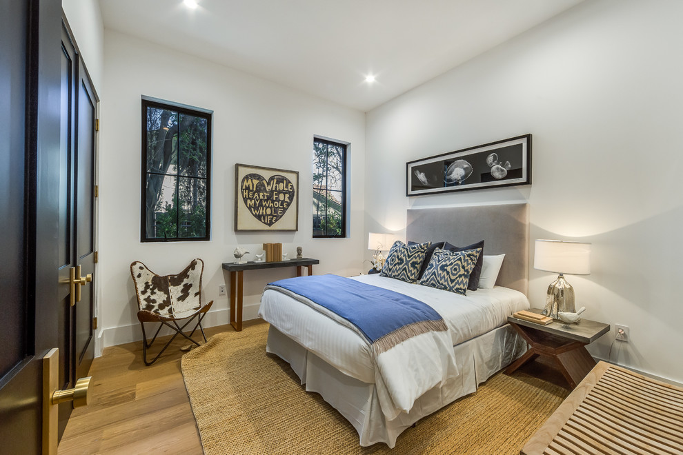 На фото: гостевая спальня среднего размера, (комната для гостей) в стиле неоклассика (современная классика) с белыми стенами, светлым паркетным полом и коричневым полом без камина с