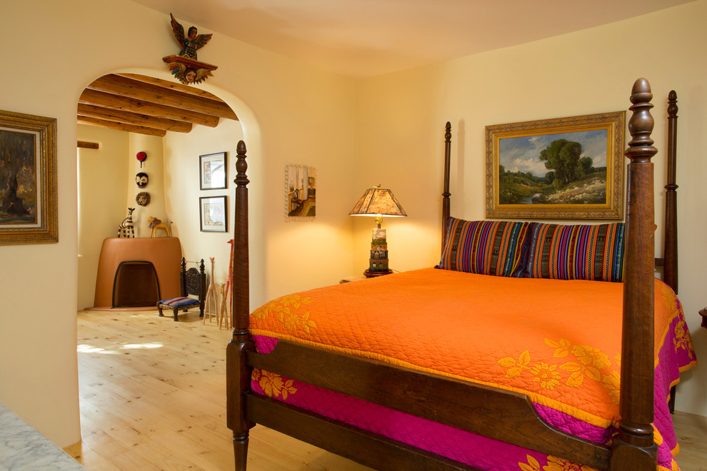 Mediterranes Hauptschlafzimmer mit beiger Wandfarbe, hellem Holzboden und Eckkamin in Sonstige