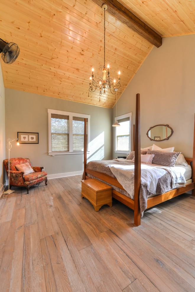 Modelo de dormitorio principal rústico grande sin chimenea con paredes grises y suelo de madera clara