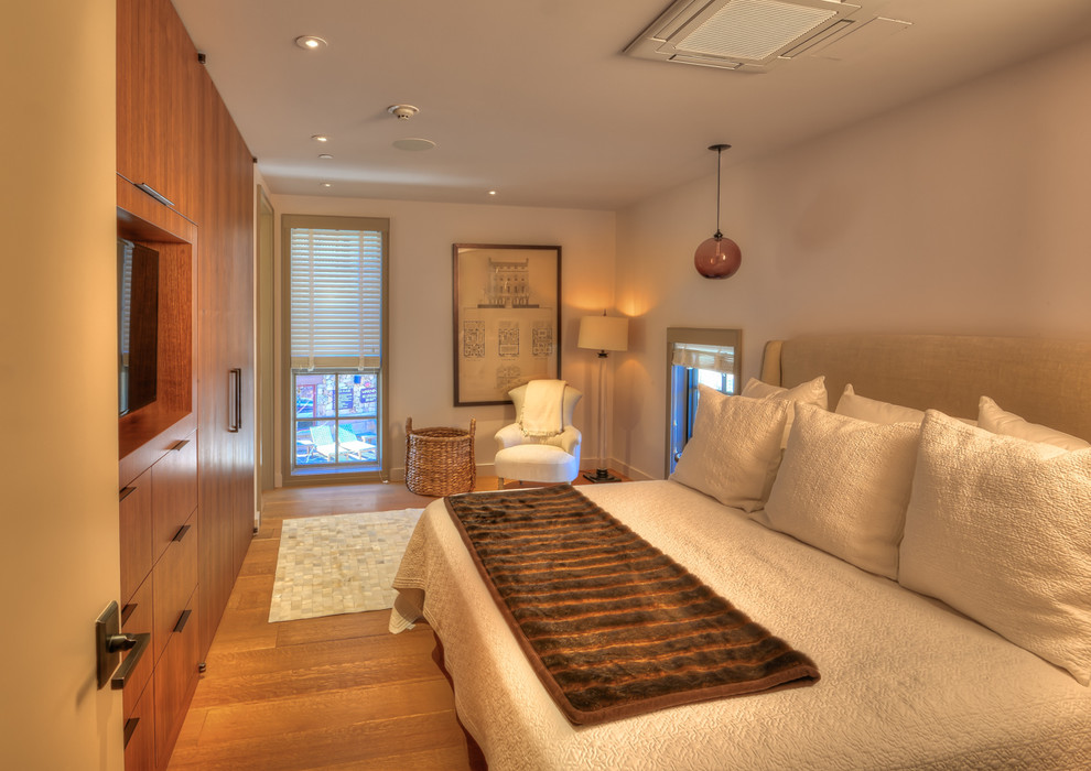 Cette image montre une chambre parentale design de taille moyenne avec un mur beige, un sol en bois brun, aucune cheminée et un sol marron.