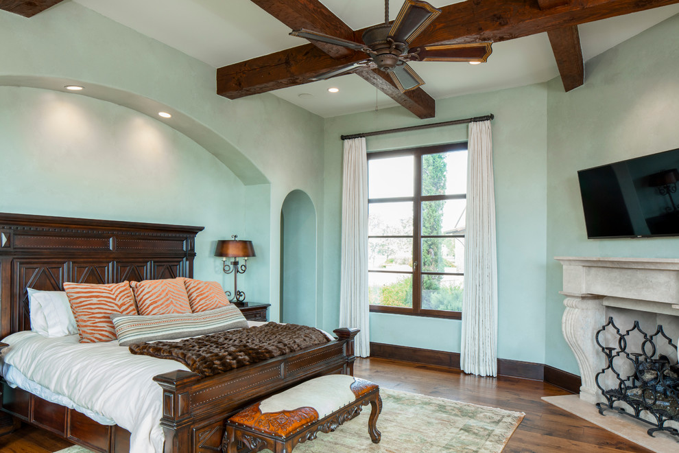 オースティンにある地中海スタイルのおしゃれな主寝室 (青い壁、濃色無垢フローリング、コーナー設置型暖炉) のレイアウト