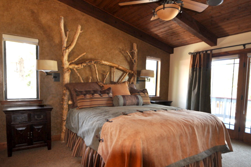 Ejemplo de dormitorio principal rústico de tamaño medio sin chimenea con paredes marrones y moqueta