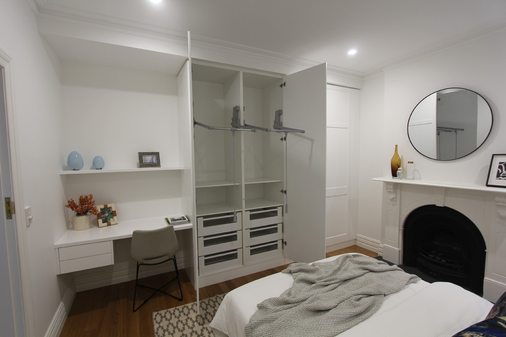 Стильный дизайн: большая гостевая спальня (комната для гостей) в стиле неоклассика (современная классика) с белыми стенами, светлым паркетным полом, стандартным камином и фасадом камина из дерева - последний тренд