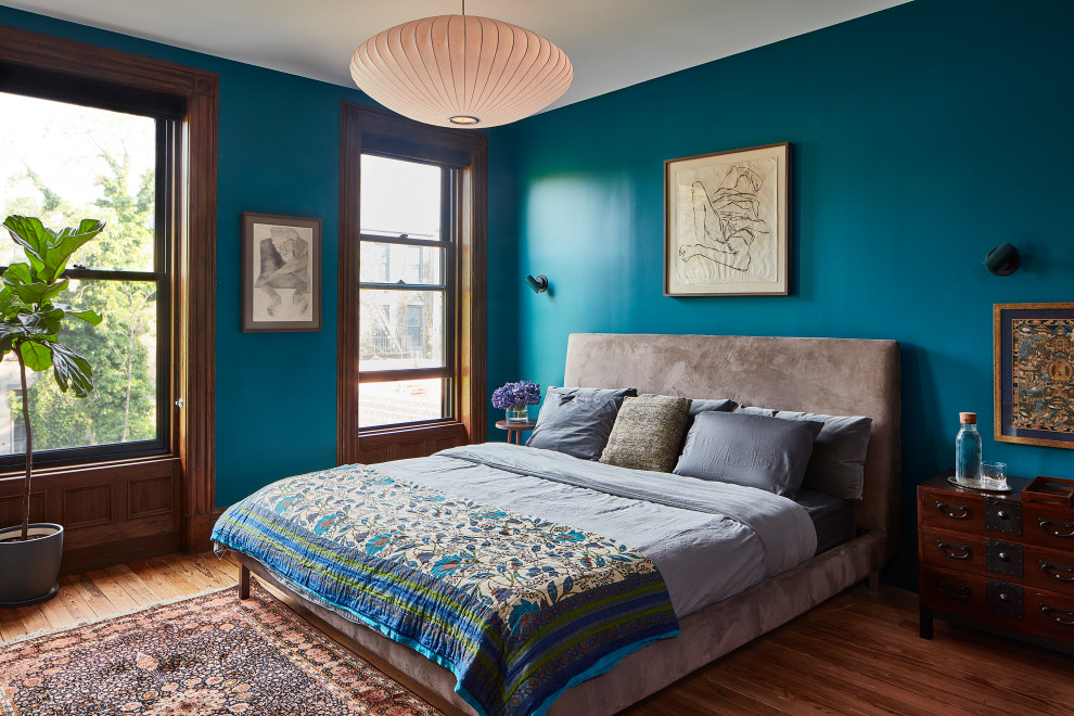 Idée de décoration pour une chambre parentale tradition avec un mur bleu et un sol en bois brun.
