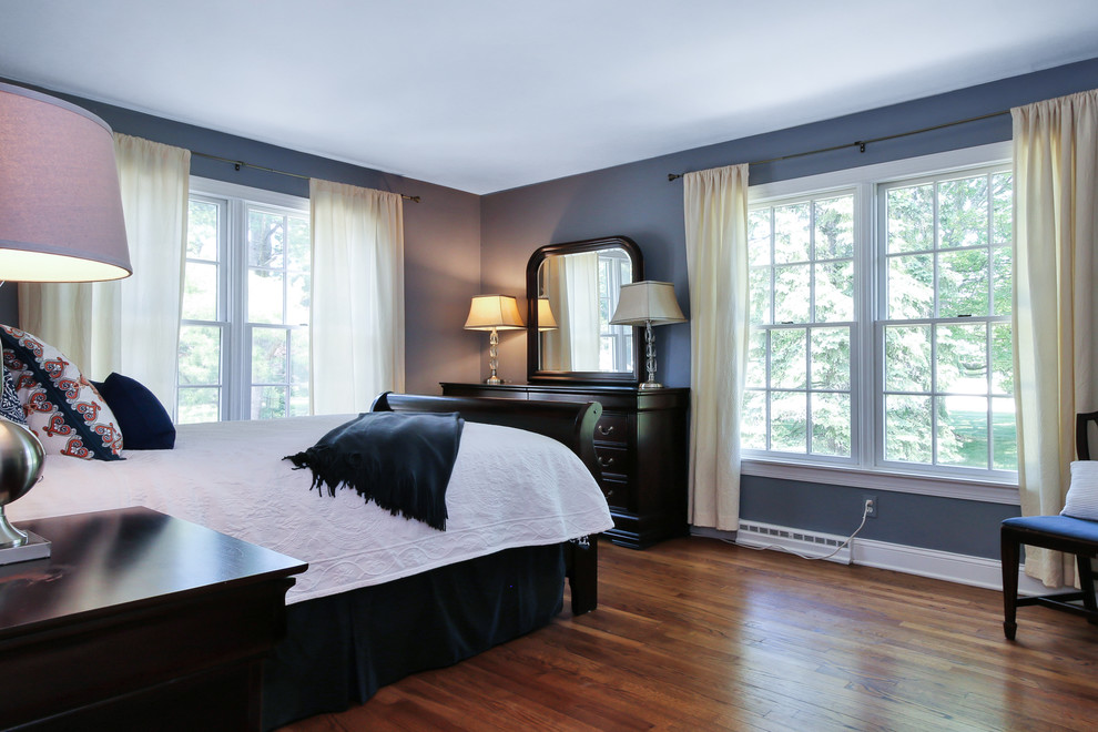 Imagen de habitación de invitados bohemia grande sin chimenea con paredes azules y suelo de madera en tonos medios