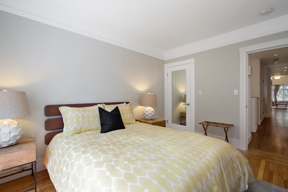 Modelo de habitación de invitados ecléctica de tamaño medio con paredes grises y suelo de madera en tonos medios
