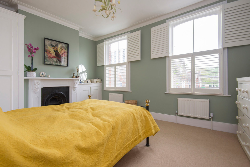 Cette photo montre une chambre avec moquette chic de taille moyenne avec un mur vert, une cheminée standard, un manteau de cheminée en pierre et un sol beige.