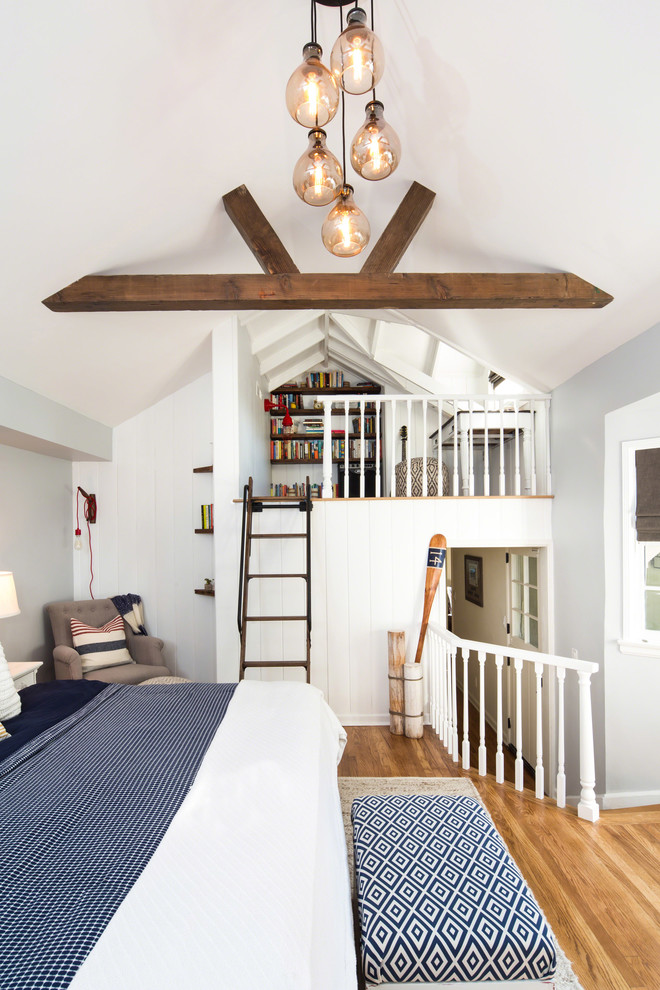 Immagine di una piccola camera da letto stile loft costiera con pareti grigie, pavimento in legno massello medio e nessun camino