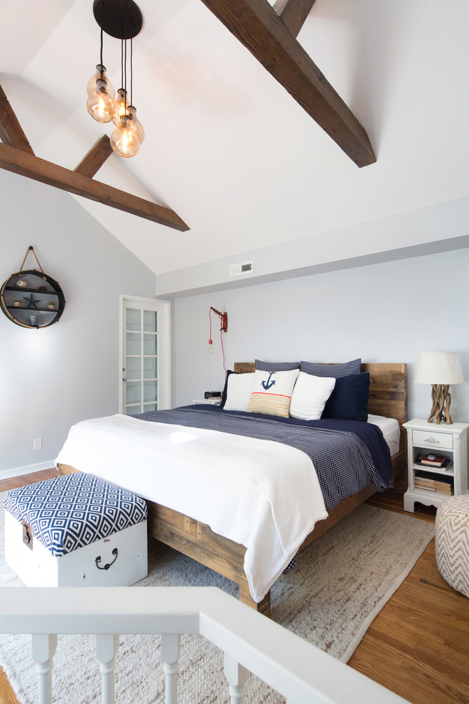 Ejemplo de dormitorio tipo loft costero pequeño sin chimenea con paredes grises y suelo de madera en tonos medios