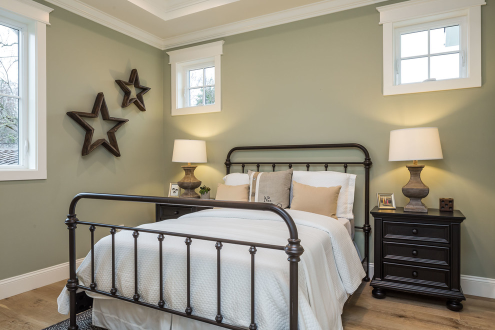 Modelo de habitación de invitados de estilo de casa de campo de tamaño medio con paredes verdes, suelo de madera clara y suelo gris