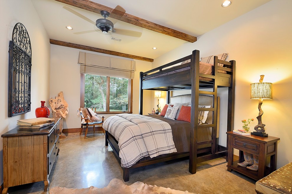Example of a large southwest guest concrete floor bedroom design in Houston with beige walls and no fireplace