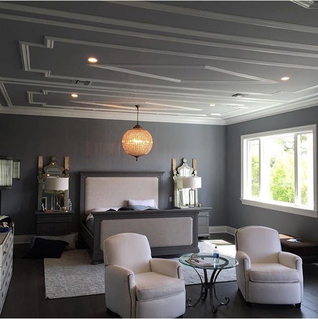 Cette image montre une grande chambre parentale design avec un mur gris, parquet foncé et un sol marron.