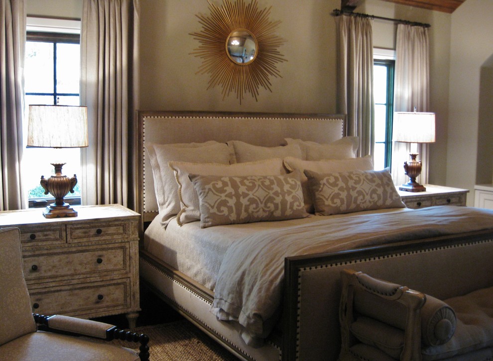 Modelo de dormitorio principal clásico grande con paredes blancas, suelo de madera oscura, chimenea de doble cara, marco de chimenea de madera y suelo marrón
