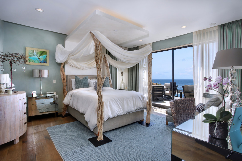 Example of a beach style medium tone wood floor and brown floor bedroom design in Orange County with gray walls