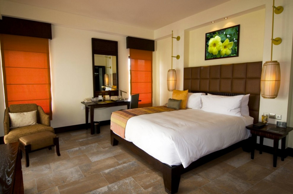 Diseño de dormitorio principal de estilo zen de tamaño medio sin chimenea con paredes beige, suelo de baldosas de porcelana y suelo marrón