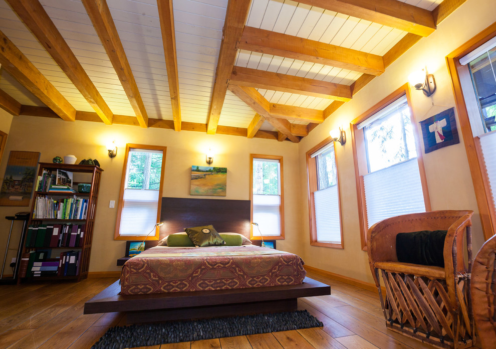 Aménagement d'une chambre d'amis contemporaine avec un sol en bois brun et poutres apparentes.
