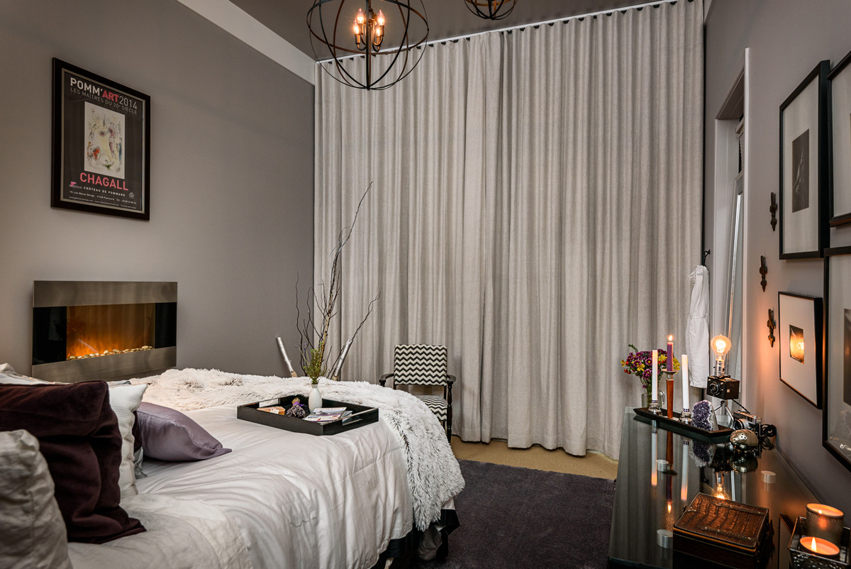 На фото: хозяйская спальня среднего размера в стиле неоклассика (современная классика) с серыми стенами, ковровым покрытием, подвесным камином, фасадом камина из металла и серым полом с