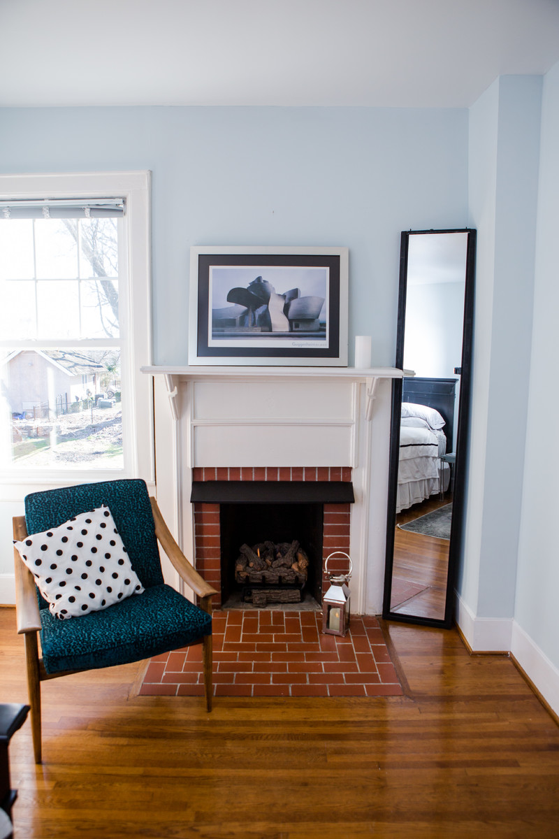Diseño de habitación de invitados tradicional renovada de tamaño medio con paredes azules, suelo de madera en tonos medios, todas las chimeneas, marco de chimenea de ladrillo y suelo blanco