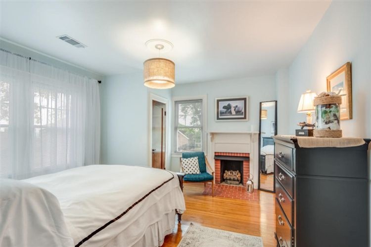 Foto de dormitorio principal costero de tamaño medio con paredes azules, suelo de madera en tonos medios, todas las chimeneas, marco de chimenea de ladrillo y suelo rosa