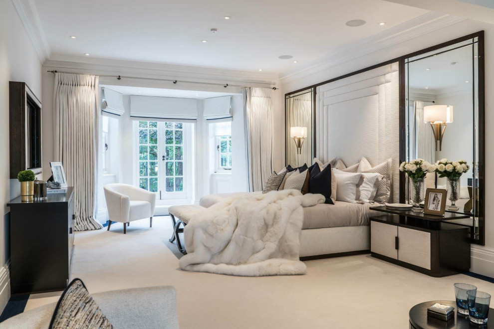 Large contemporary master bedroom in London with beige walls, carpet and beige floors.
