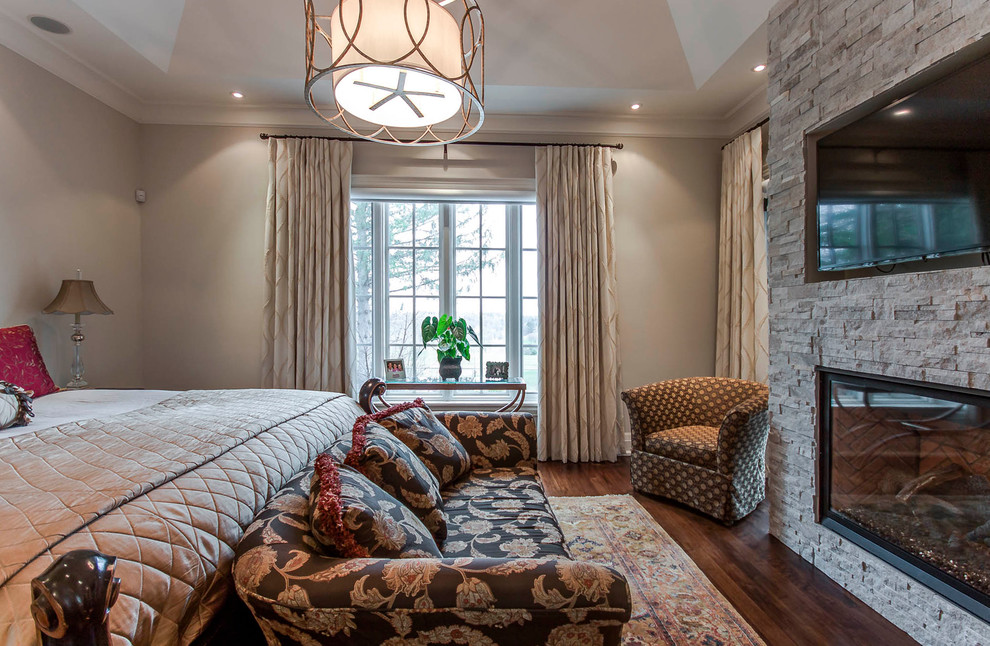 This is an example of a medium sized retro master bedroom in Toronto with beige walls, dark hardwood flooring, a standard fireplace and a stone fireplace surround.