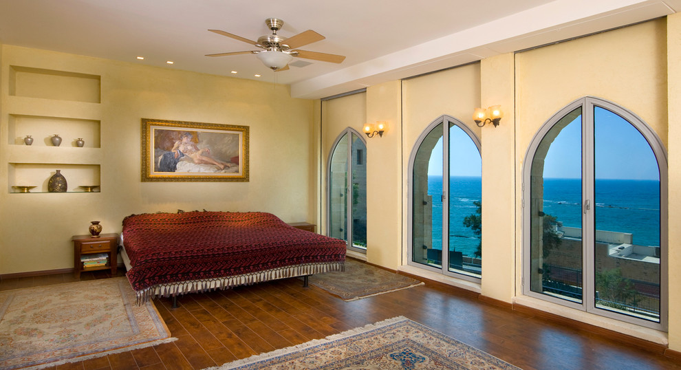 Cette photo montre une chambre méditerranéenne avec un mur beige et parquet foncé.