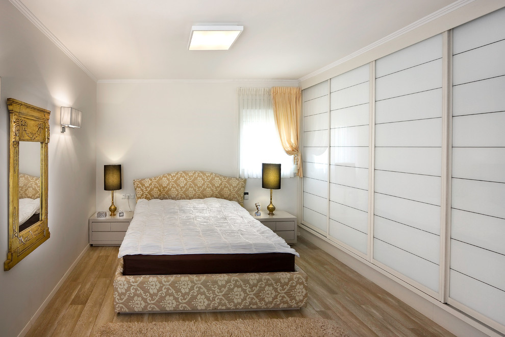 Eklektisk inredning av ett sovrum, med vita väggar och ljust trägolv