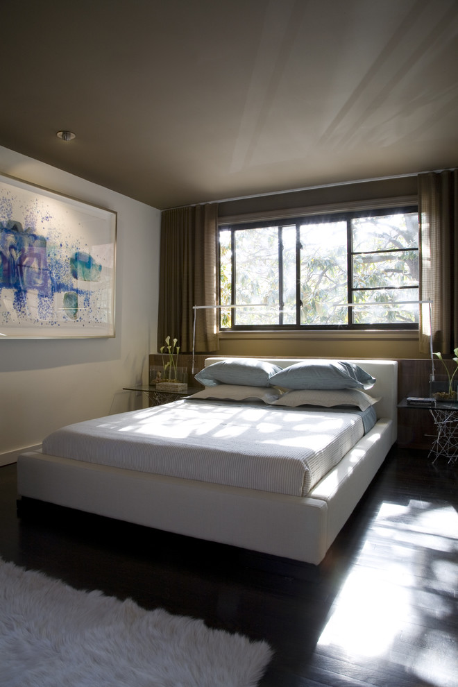 Cette image montre une chambre design avec un mur blanc et parquet foncé.