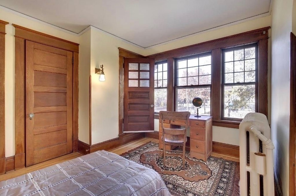 Diseño de habitación de invitados de estilo americano de tamaño medio sin chimenea con paredes beige, suelo de madera clara y suelo beige
