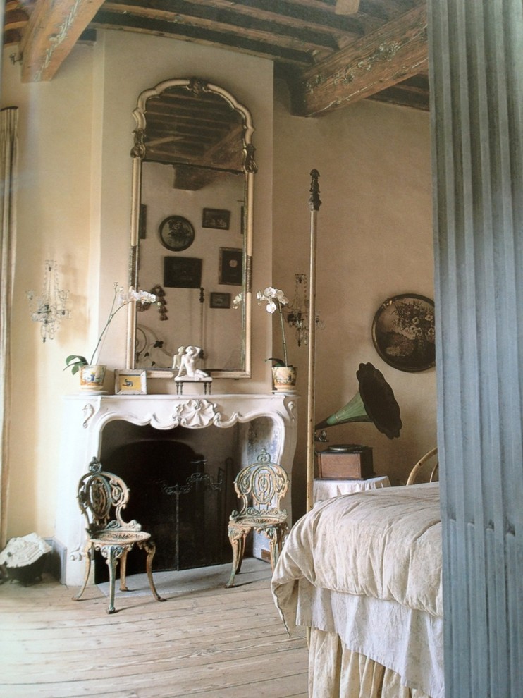 Diseño de dormitorio principal mediterráneo con marco de chimenea de piedra