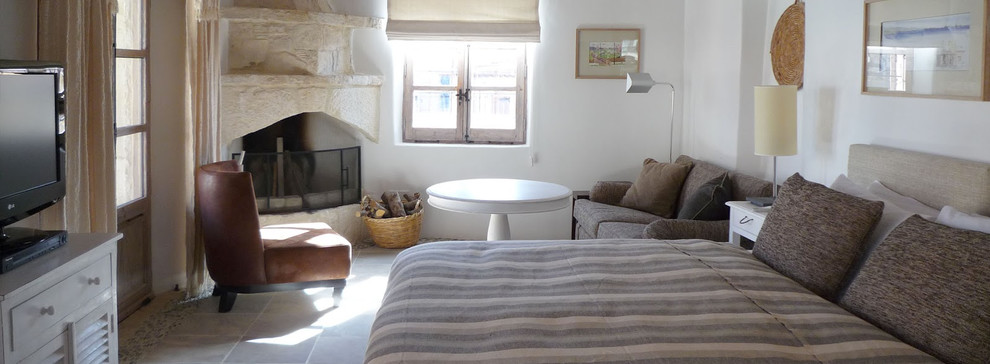 Imagen de dormitorio principal mediterráneo con marco de chimenea de piedra